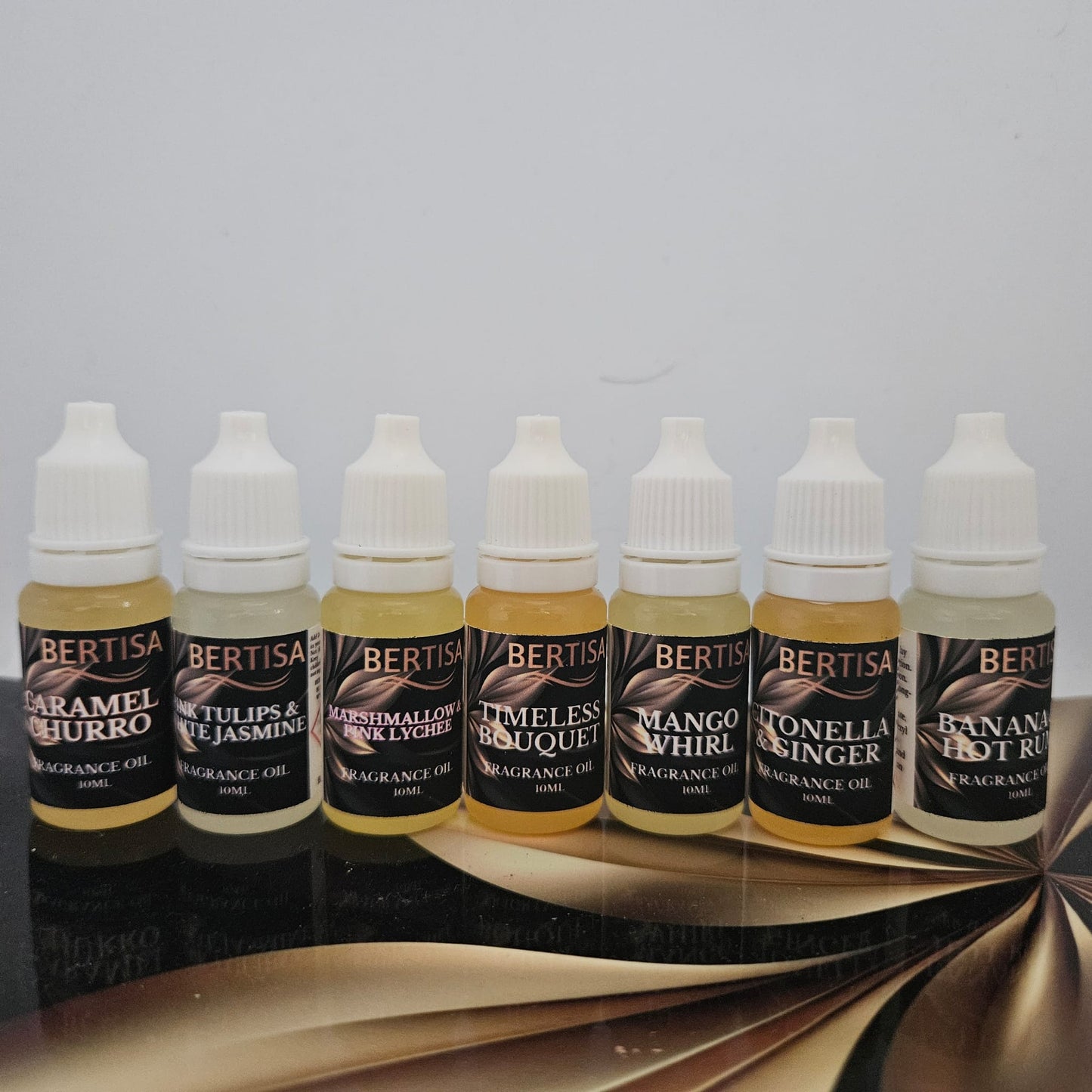 Set of Bertisa fragrance oil bottles on a reflective surface with a neutral background