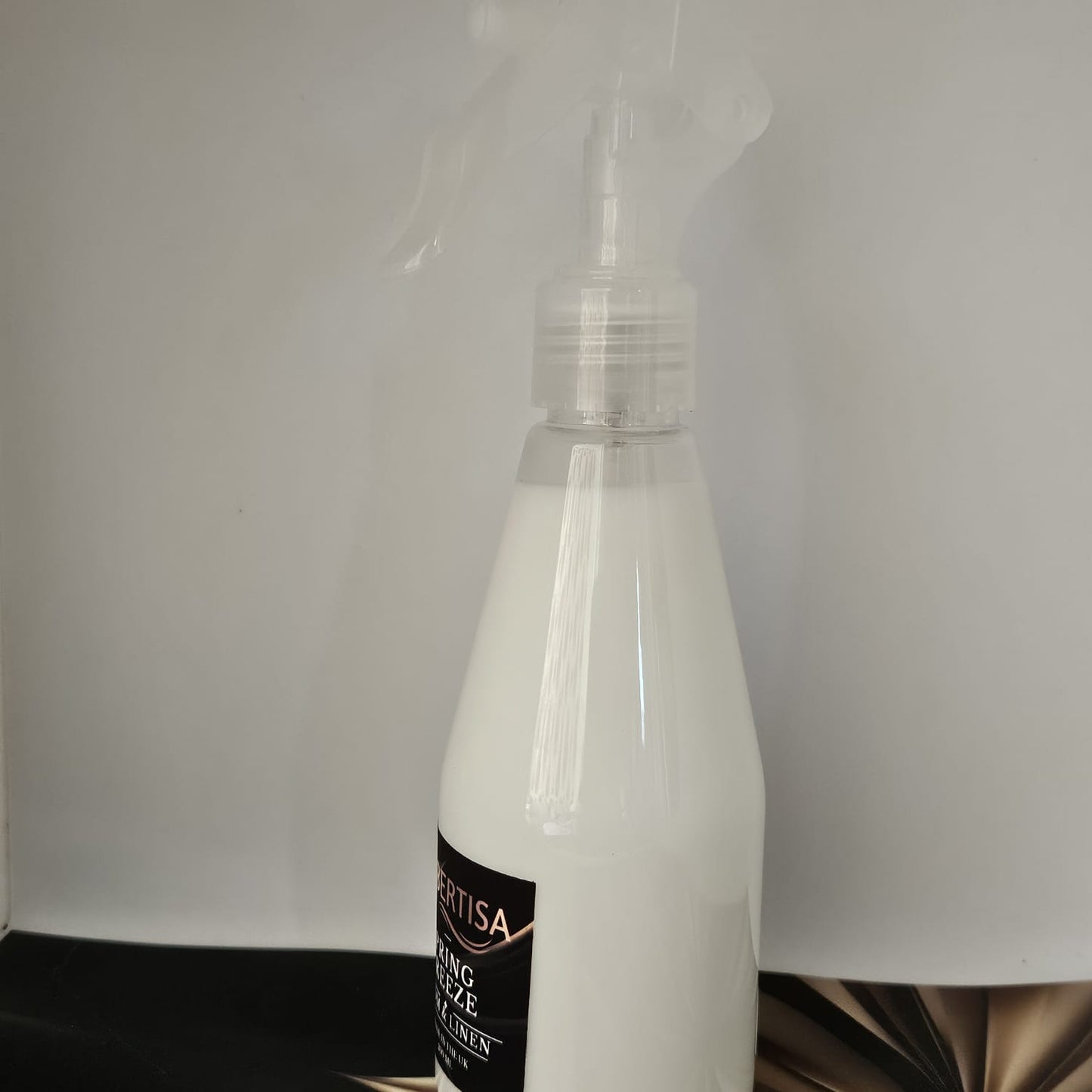 Clear spray bottle with a black label on a white background