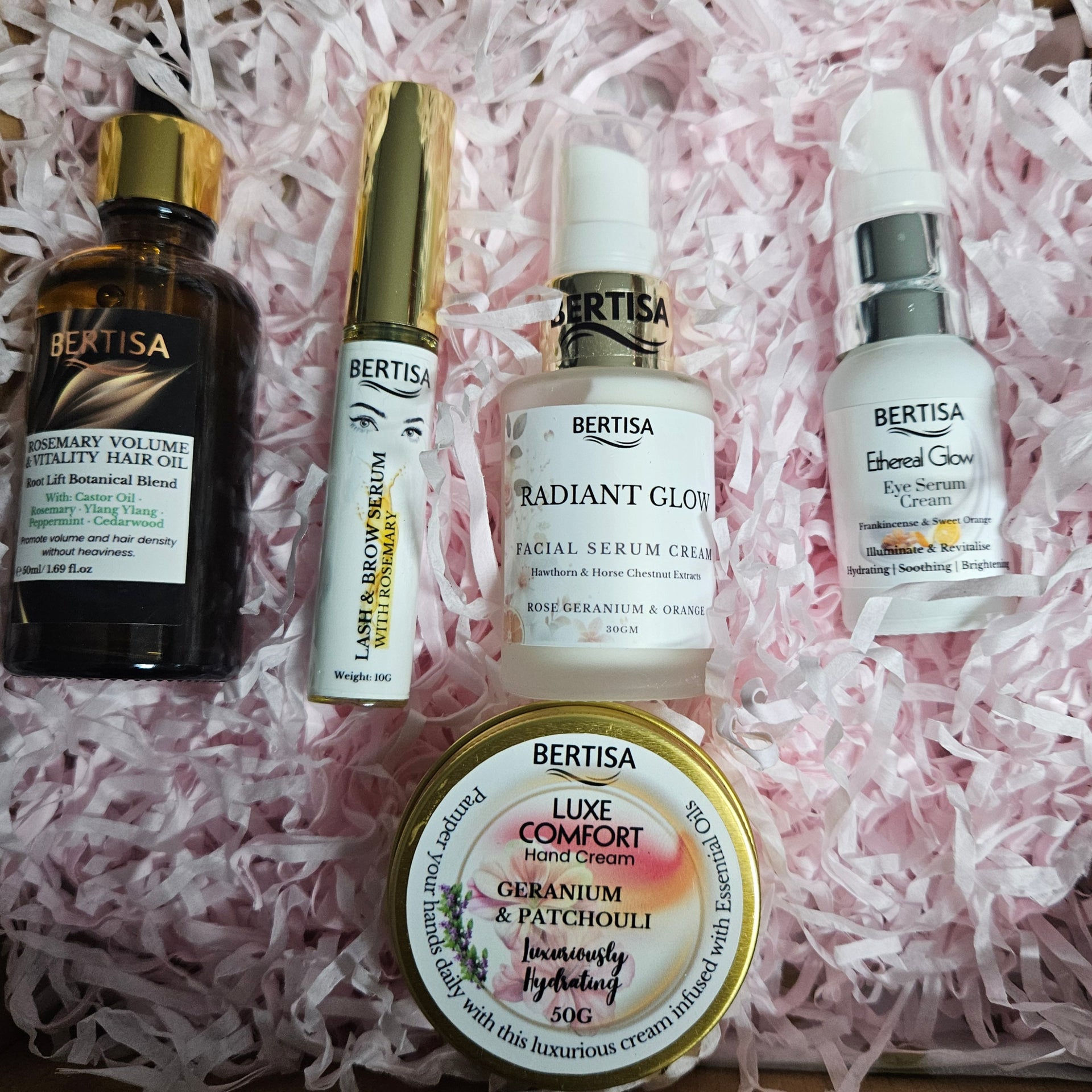 Collection of Bertisa skincare and beauty products on pink shredded paper