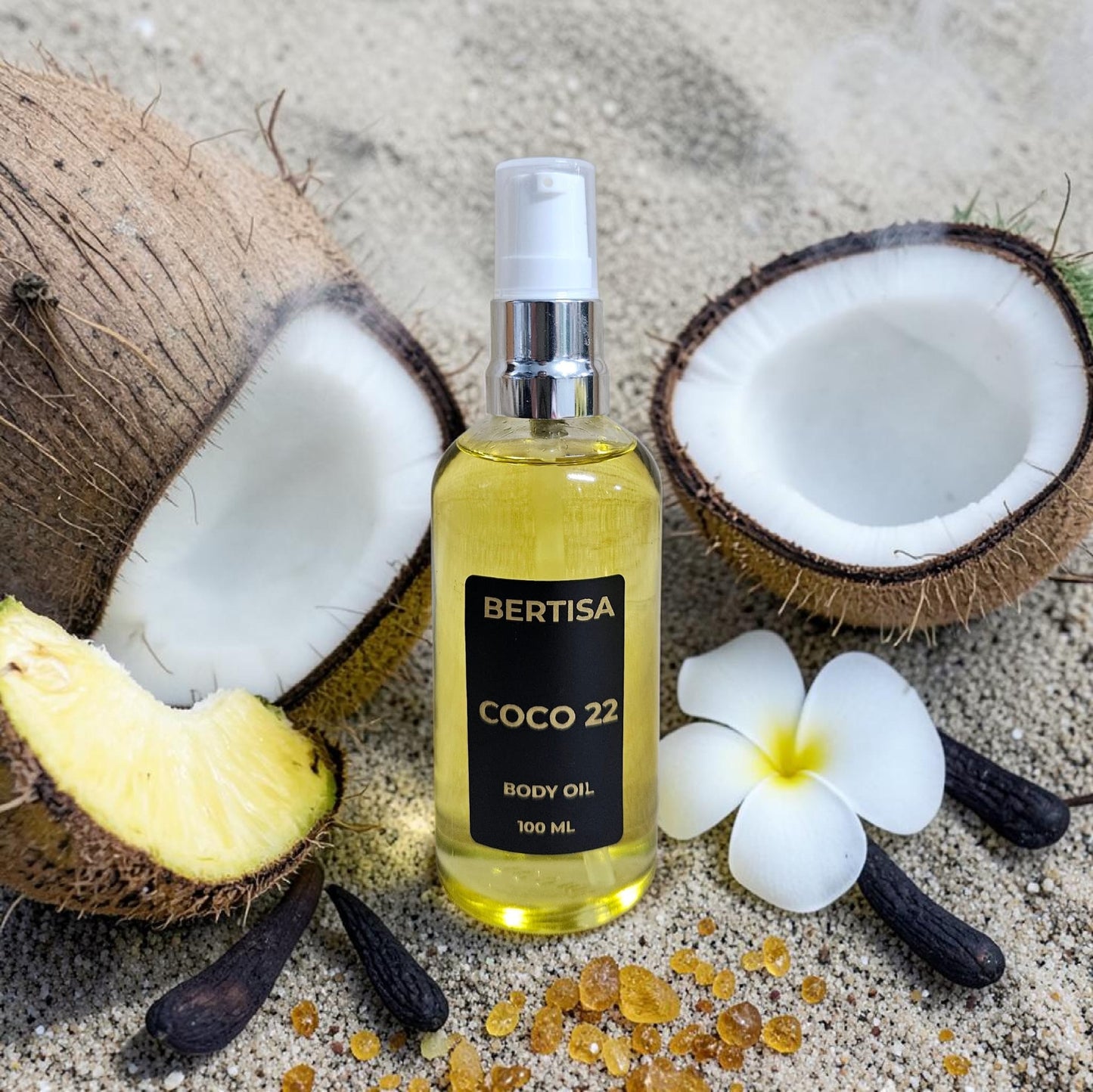 Bottle of Bertisa Coco 22 body oil with coconuts and a flower on a textured surface