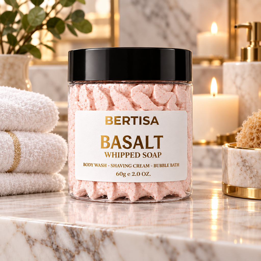 Pink whipped soap jar on marble counter with towels and sea sponge