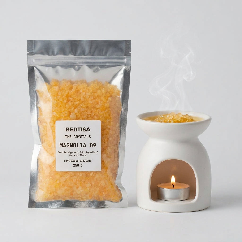 Magnolia 09 fragranced sizzlers in a clear bag with yellow crystals, next to a ceramic oil burner giving off steam