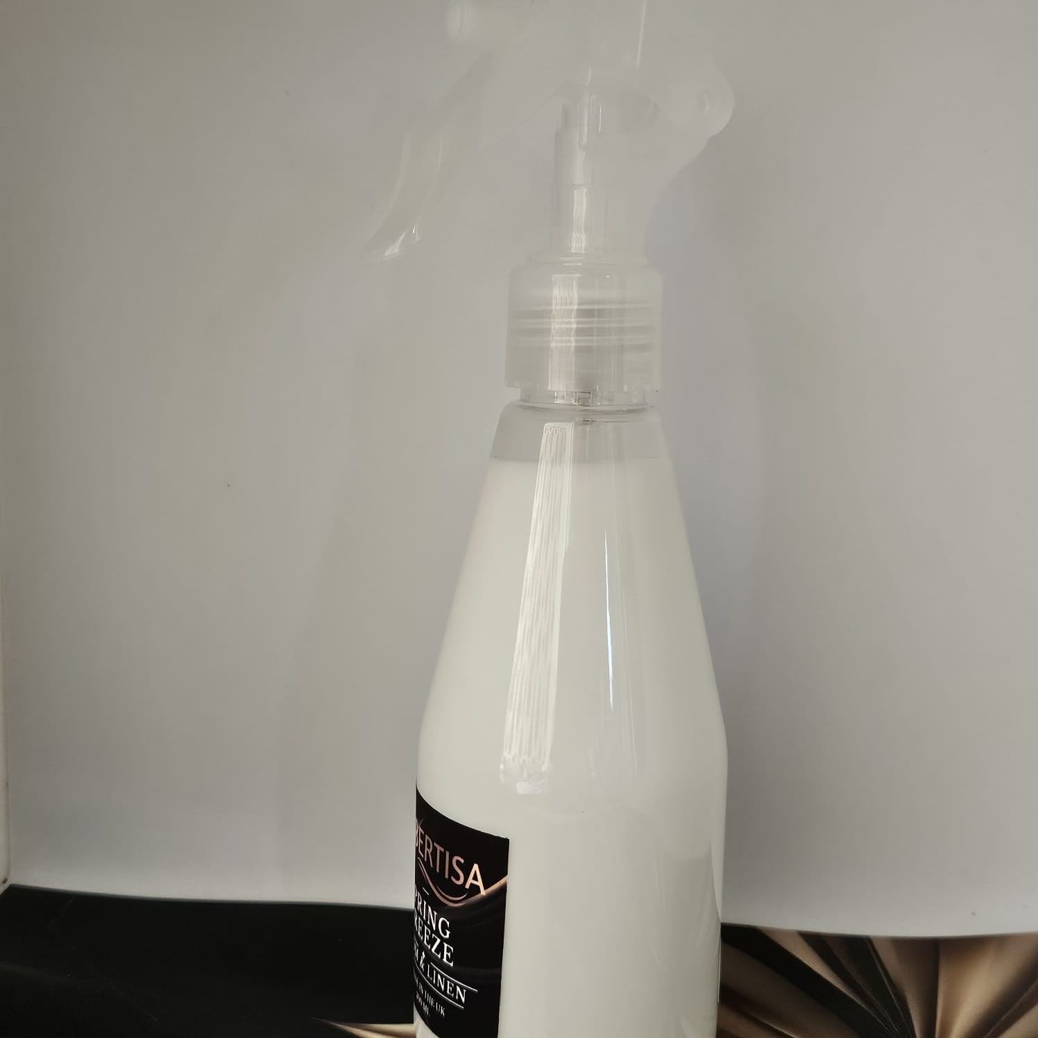 Clear spray bottle with a black label on a white background